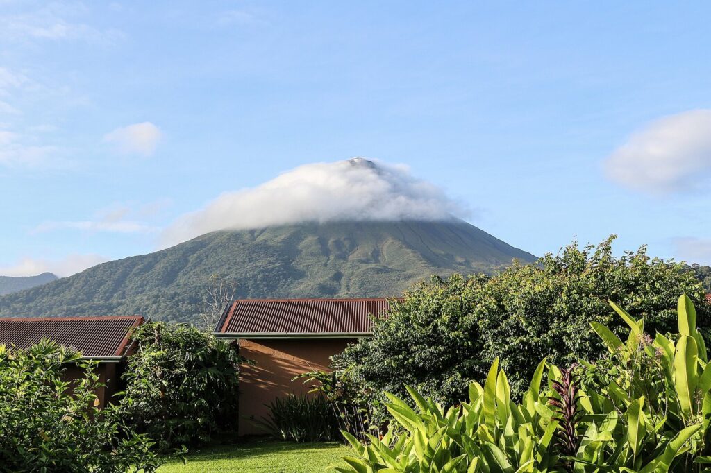 Volcán Arenal en Costa Rica, con la cima entre nubes y vegetación tropical en primer plano