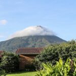Volcán Arenal en Costa Rica, con la cima entre nubes y vegetación tropical en primer plano