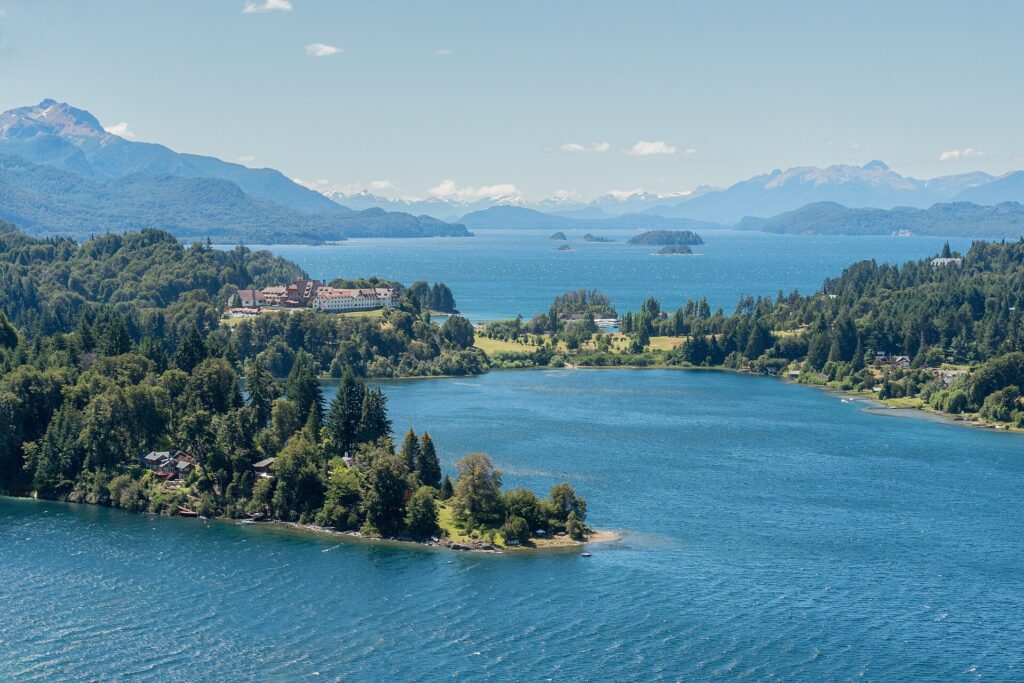 Bariloche desde Perú: península de Llao Llao cubierta de bosque entre lagos azules, con un gran hotel de techos rojos y montañas al fondo