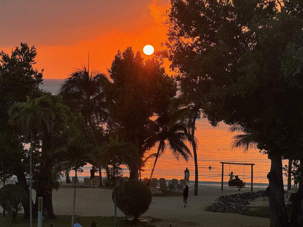 Playa de Negril en Jamaica con arena clara, mar turquesa y vegetación al fondo bajo cielo azul