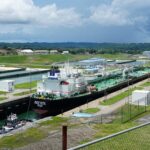 Buque cisterna cruzando las esclusas Agua Clara del Canal de Panamá, con colinas verdes al fondo