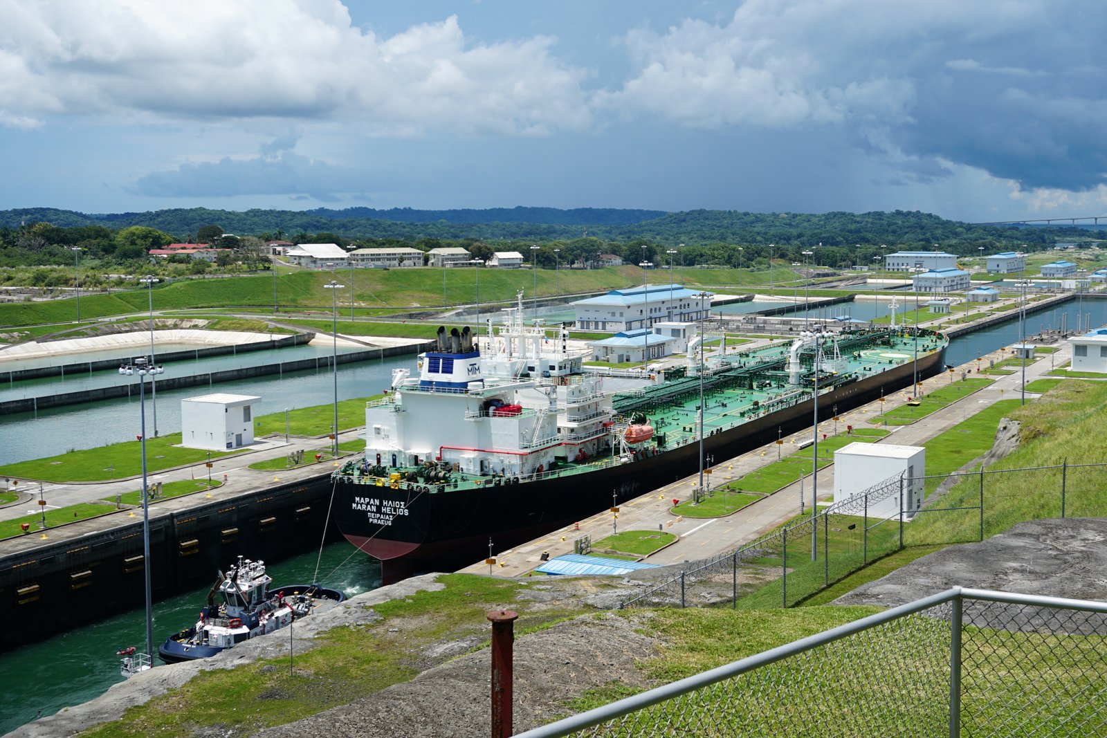 Buque cisterna cruzando las esclusas Agua Clara del Canal de Panamá, con colinas verdes al fondo