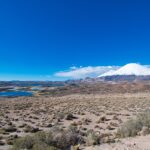 Parque Nacional Lauca: el volcán Parinacota cubierto de nieve se alza tras lagunas azules y una planicie de arbustos secos, bajo un cielo azul intenso